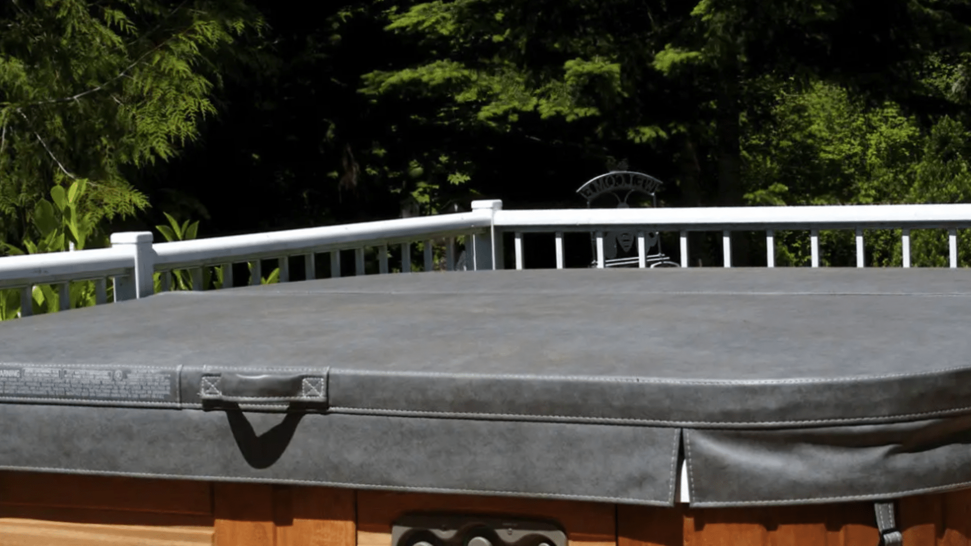 Hot tub on deck under blue sky near white vinyl fence. Cover is off after easy removal, showcasing hot tub cover options at Nejame & Sons in Danbury, CT & Carmel, NY.