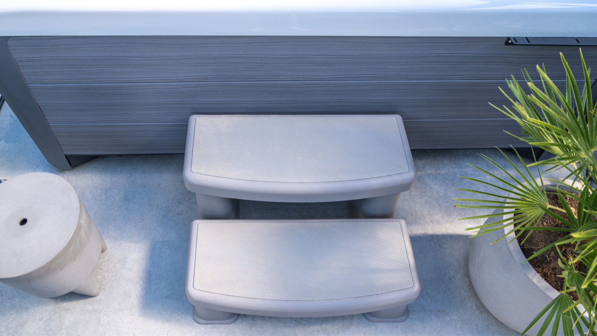 Hot tub on deck under blue sky near white vinyl fence. Cover is off after easy removal, showcasing hot tub cover options at Nejame & Sons in Danbury, CT & Carmel, NY.