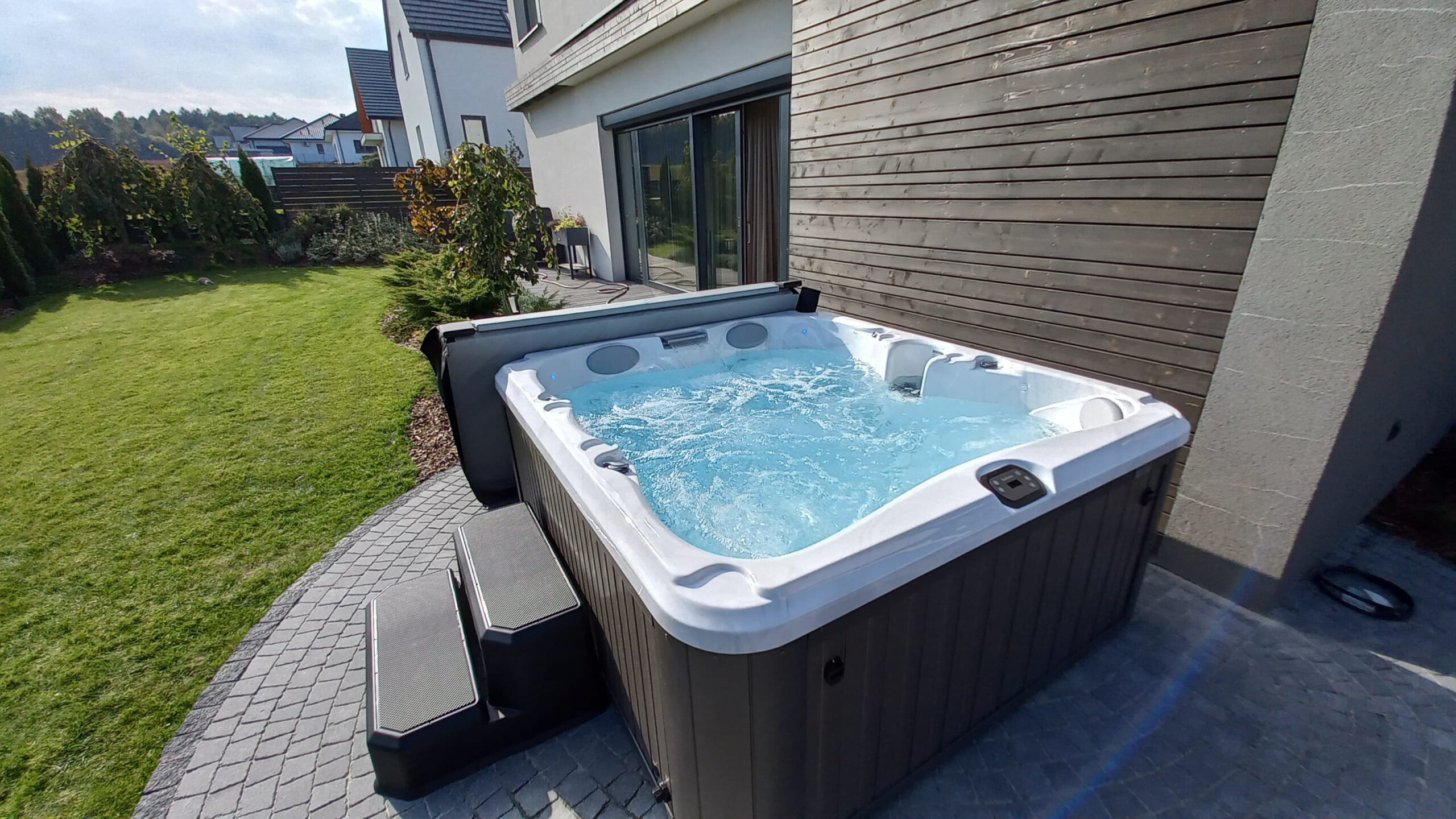 Backyard of a family home in Yorktown Heights, NY. Shows family hot tub, hot tub seating, and other recreational activites in the back including a trampoline, garden, shed, and chicken coop.