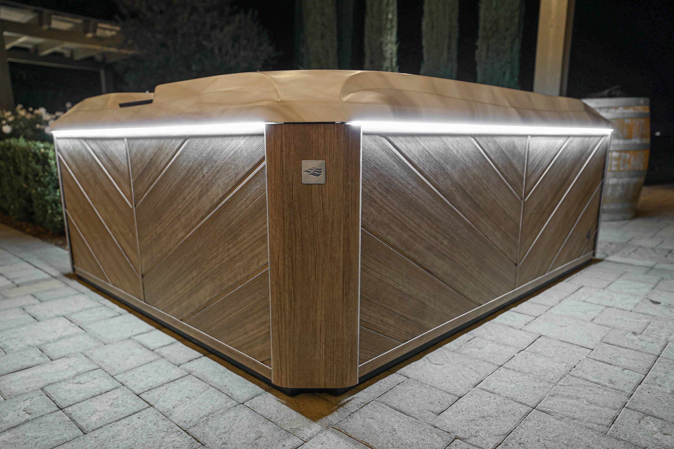 Close hot tub at a Newtown, CT home whith bright led lighting beneath cover, illuminating brown paneled exterior resembling wood.