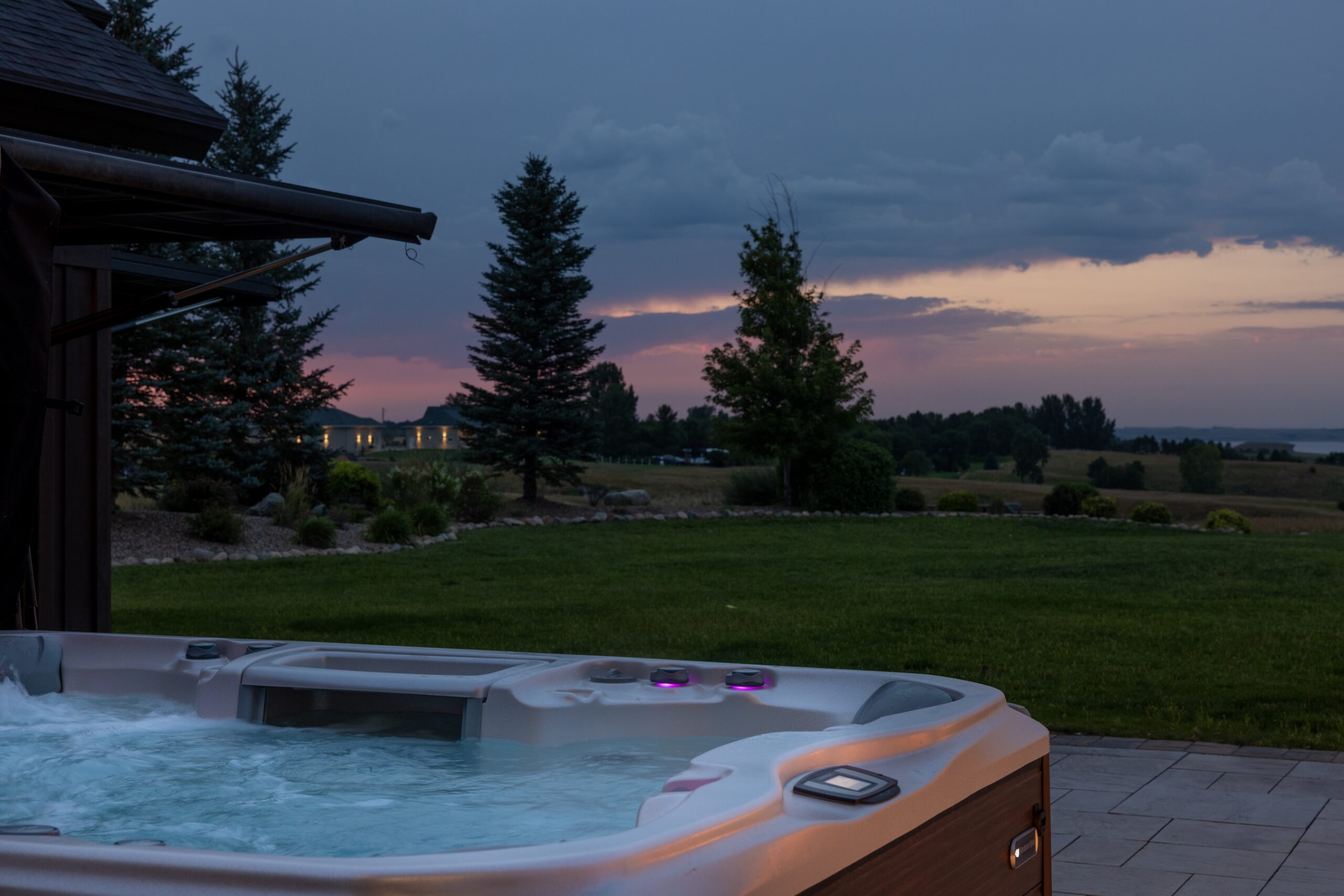 Ridgefield CT home at dusk. Shows open backyard with purple cluds and a pink sky and open hot tub in bottom left corner.