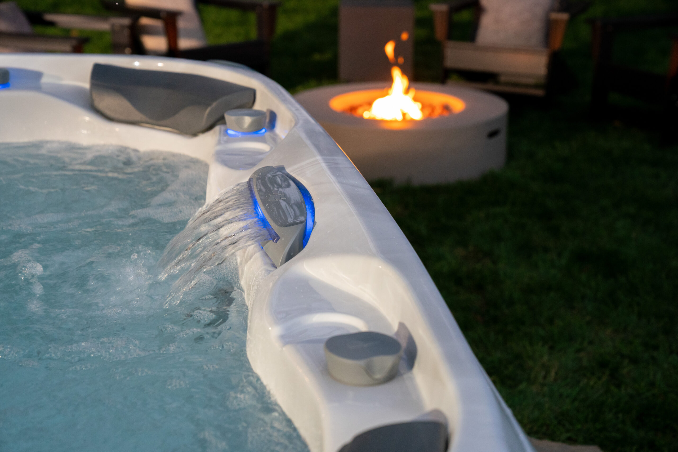 Up close of hot tub headrests and small waterfall feature with bonfire blurred in the back yard of this Mahopac, NY home.