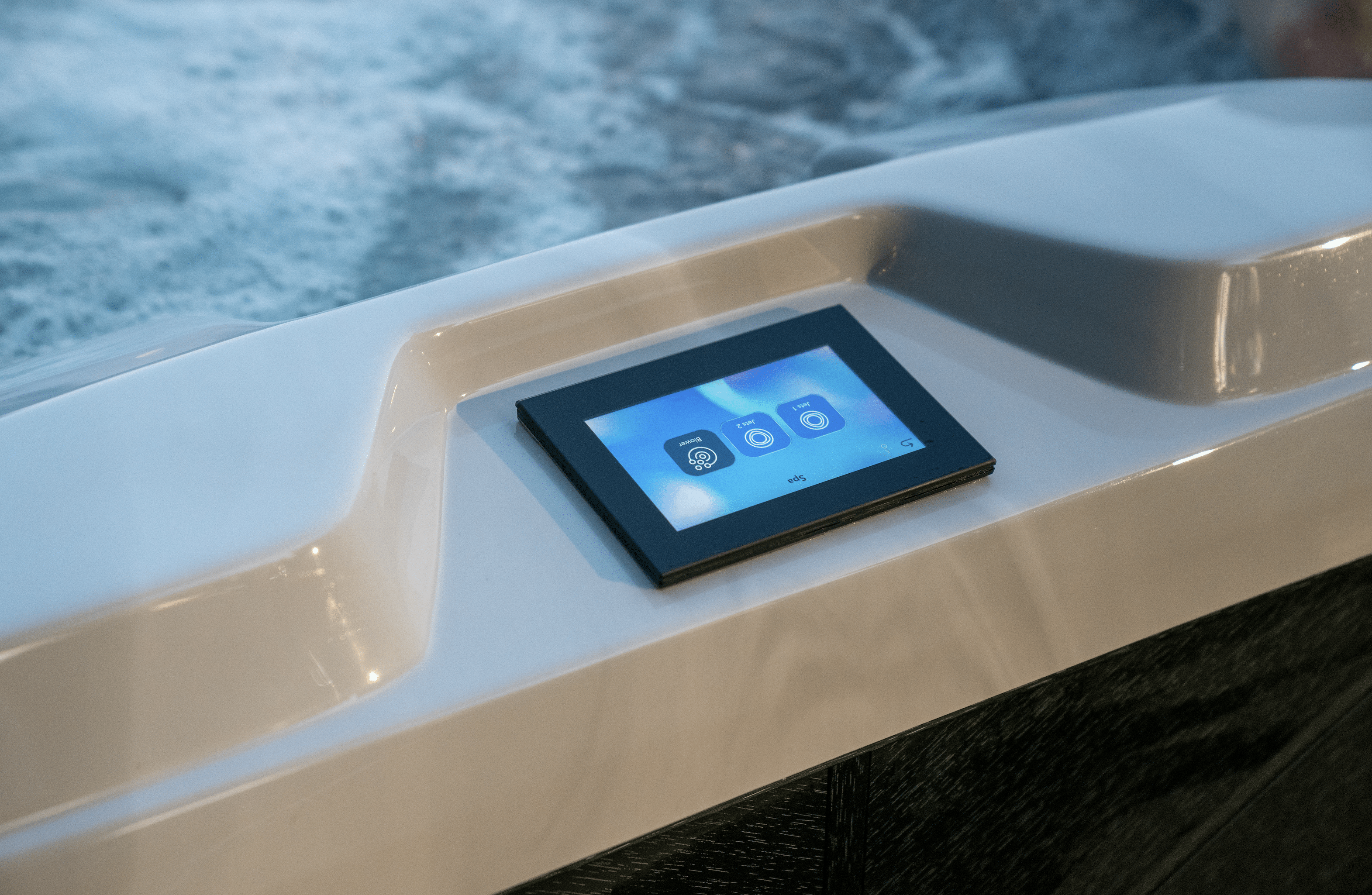 Up-close image of touch screen hot tub control panel at a Ridgefield, CT home. Rectangular panel features three jet options on the screen. Sliver of bubbly water in background.